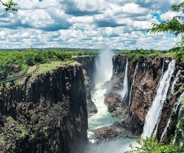 Mighty Victoria Falls with clouds of thunder. Water is falling and rises up again on the wind. A thunderous place to marvel about the sounds, views and all its powers. The Zambezi will continue its journey to the ocean while I'll keep staring into the distance.